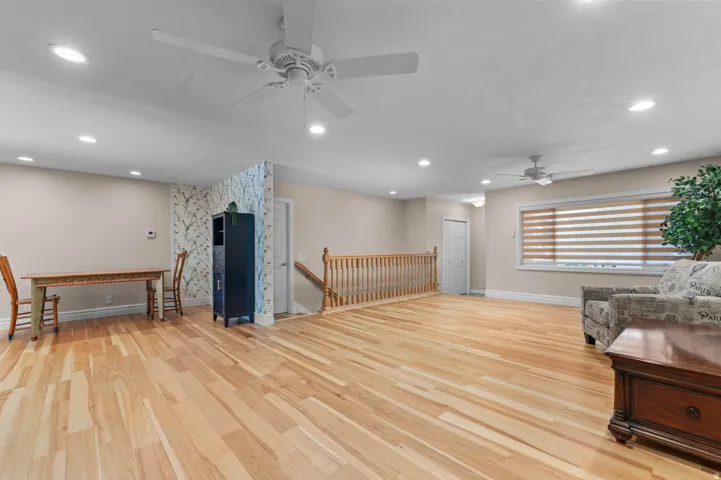 Spacious room featuring light wood-finish flooring, recessed lighting, and multiple ceiling fans