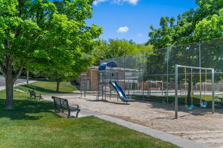 Recreational area featuring a sand play surface, a blue slide, and swing sets