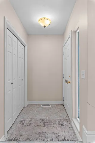 Entryway featuring diamond-set tile flooring, a flush-mount ceiling light fixture, bi-fold closet doors, a paneled entry door with brass hardware, and a sidelight window
