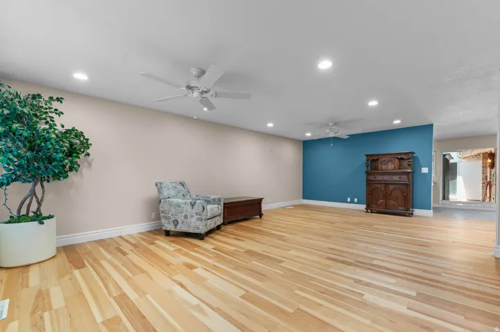 Spacious room featuring natural wood-finish flooring, recessed lighting, and a ceiling fan