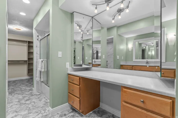 Bathroom with a dual vanity featuring wood cabinetry and white countertops