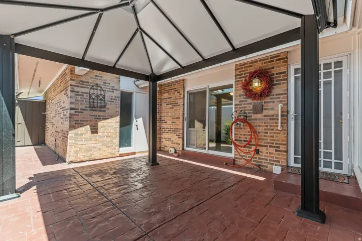 Covered patio featuring a stamped concrete surface and an exposed brick exterior