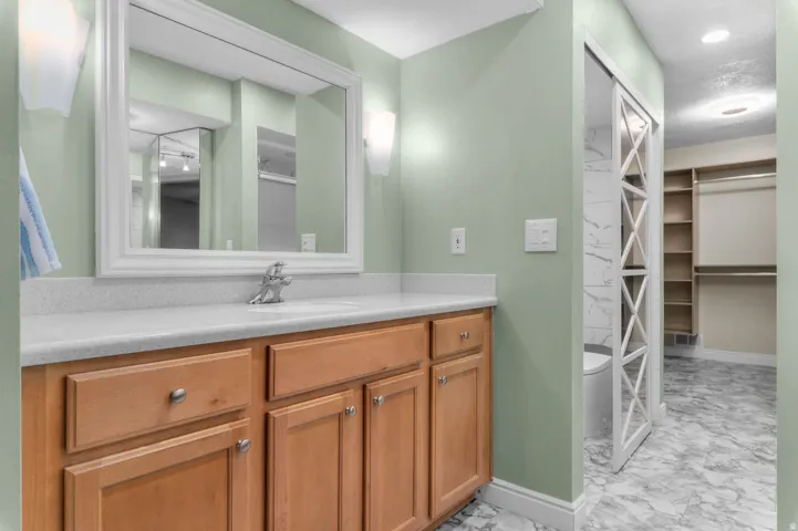 Bathroom vanity with an integrated sink, light-toned countertop, and wood-finish cabinetry