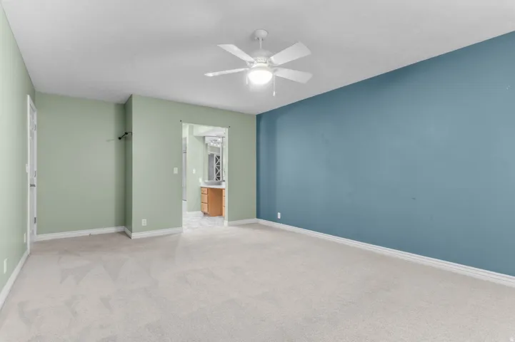 Spacious room featuring light-colored carpeting and a ceiling fan with integrated lighting