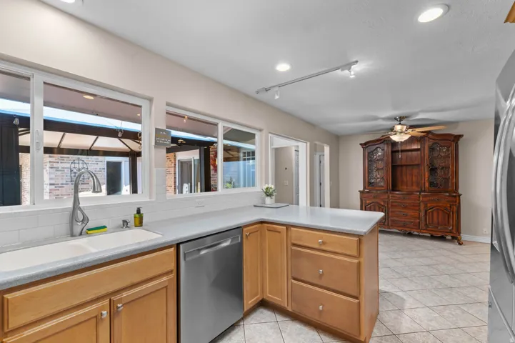 Kitchen featuring light wood cabinetry, light countertops, a white subway tile backsplash, and a stainless steel dishwasher