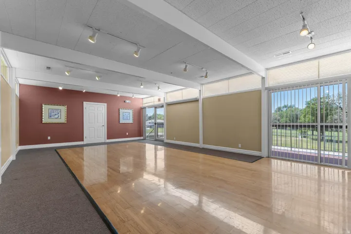 Club House Spacious interior featuring a large wood-finish dance floor with surrounding carpeted areas