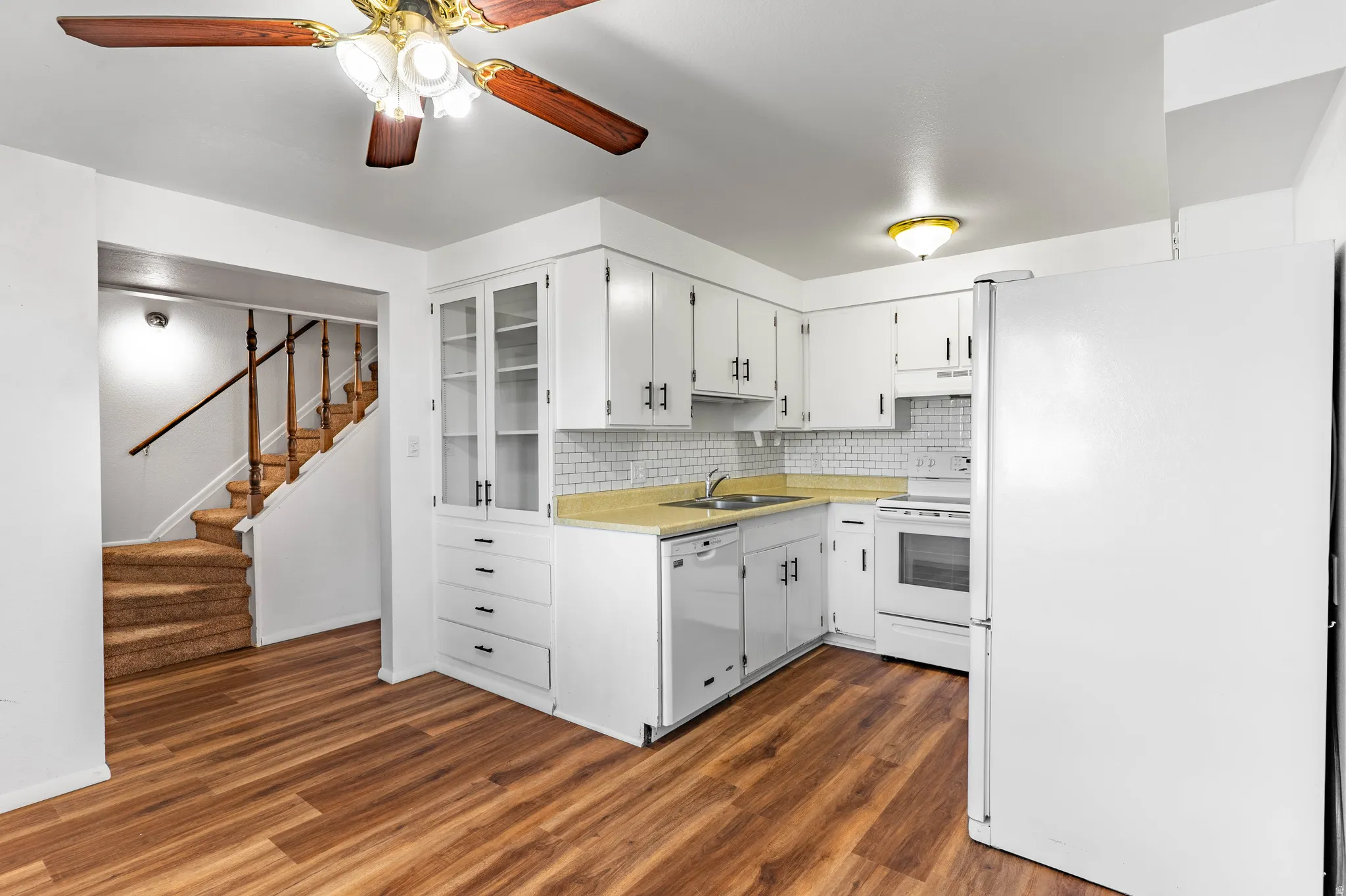 Kitchen featuring white cabinetry, white appliances, light-colored countertops, and white subway tile backsplash