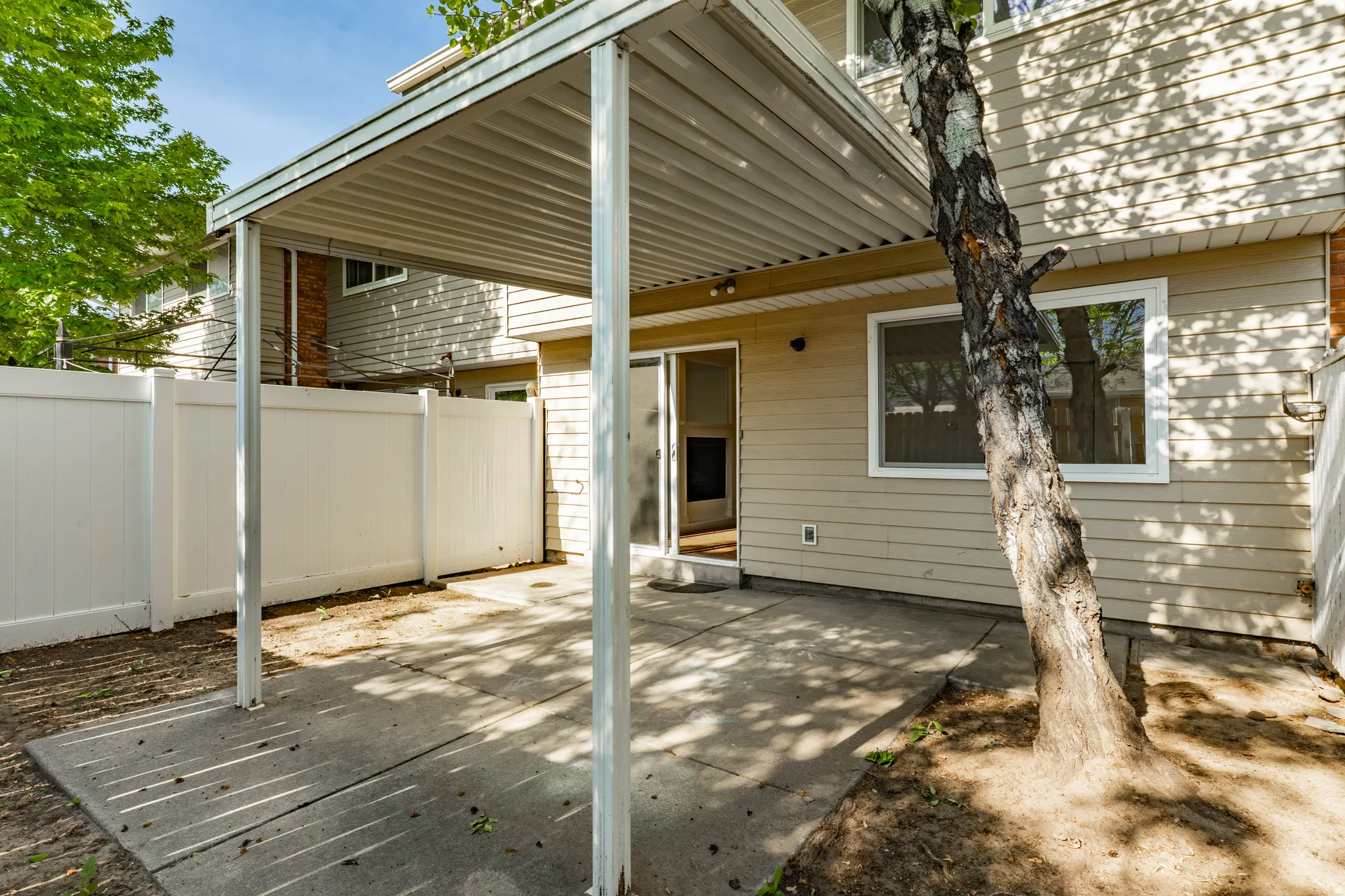 Covered concrete patio with white vinyl fencing