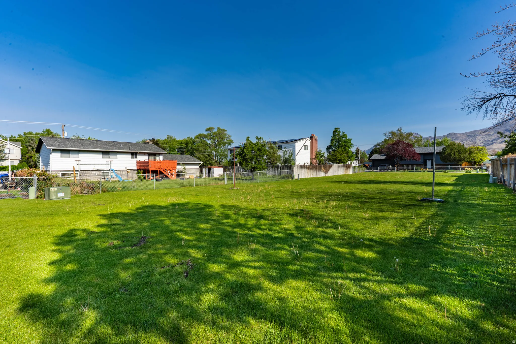 Expansive green space featuring a level lawn and mature perimeter trees