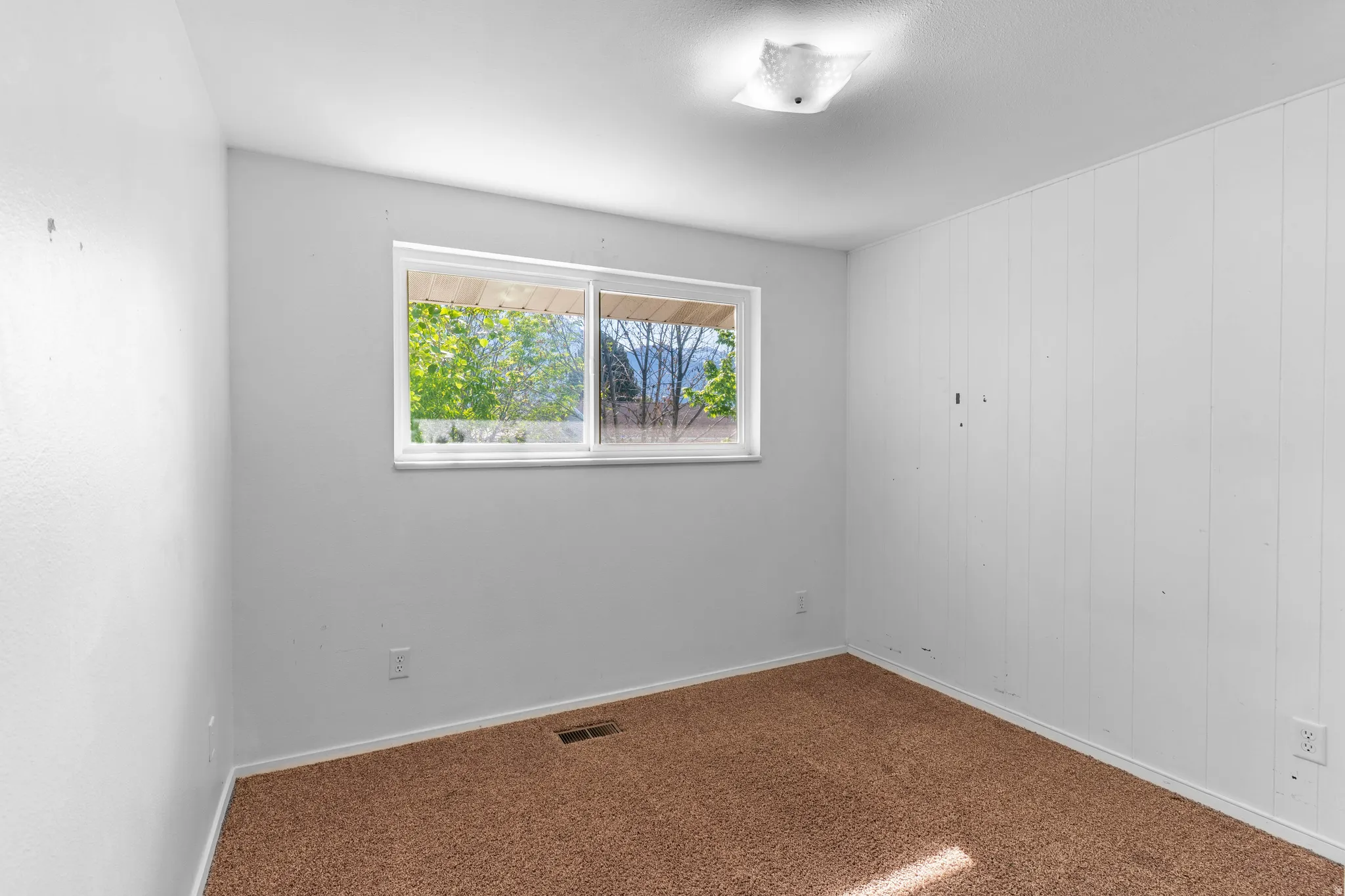 Room featuring a single horizontal window, overhead flush-mount lighting, and wall-to-wall carpeting