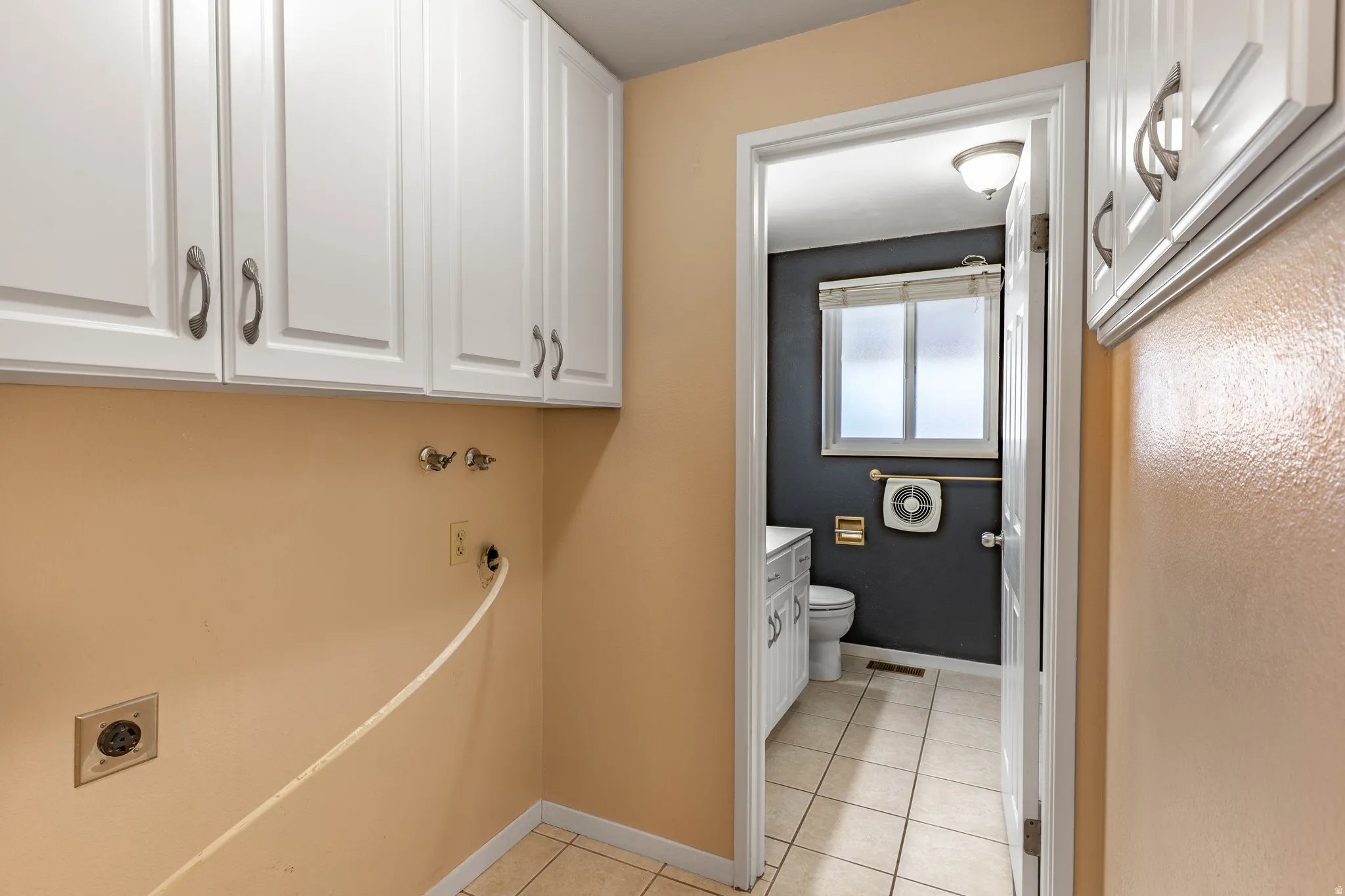 Laundry area featuring upper cabinetry with brushed nickel hardware, wall-mounted utility hookups, and ceramic tile flooring