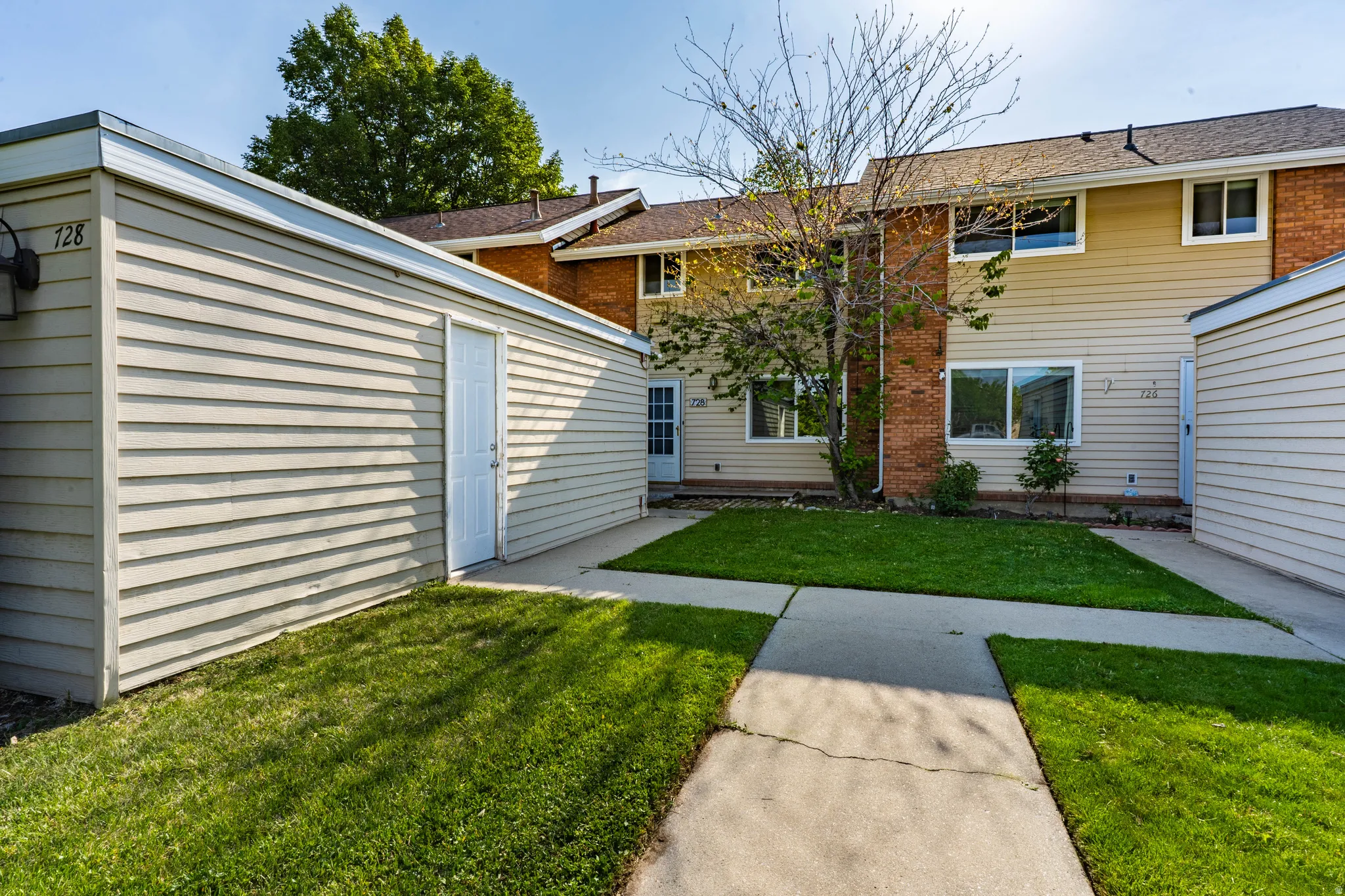 Private patio area featuring a concrete pathway and manicured lawn