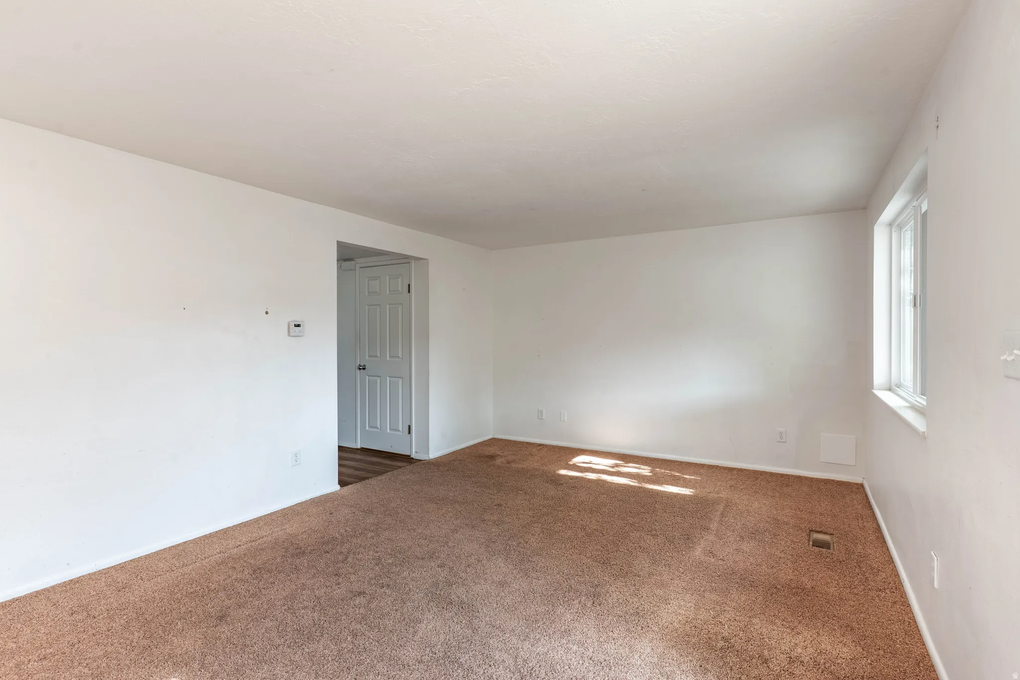 Room featuring neutral wall tones, brown carpet flooring, and a single pane window