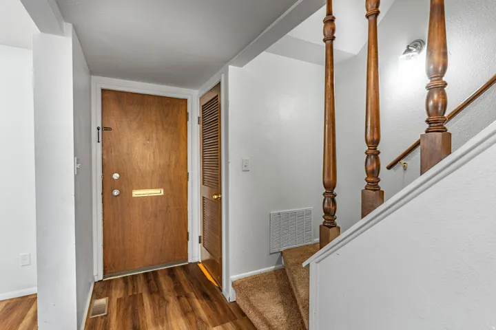 Entryway featuring wood-finish flooring, a solid wood entry door with brass mail slot, and an adjacent louvered door