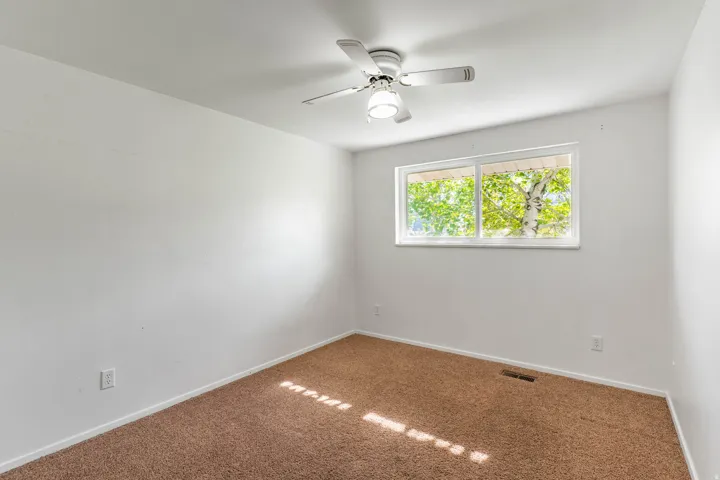Carpeted room with a ceiling fan light fixture