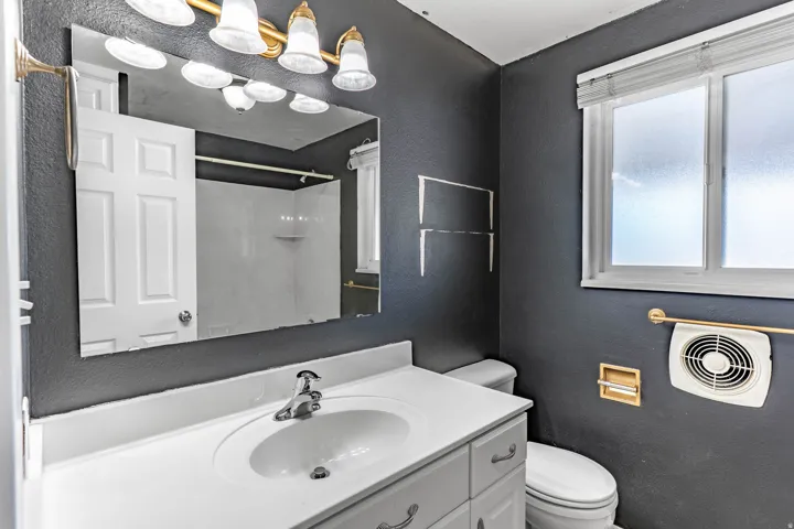 Bathroom vanity with an integrated white sink, chrome faucet, and a large wall-mounted mirror