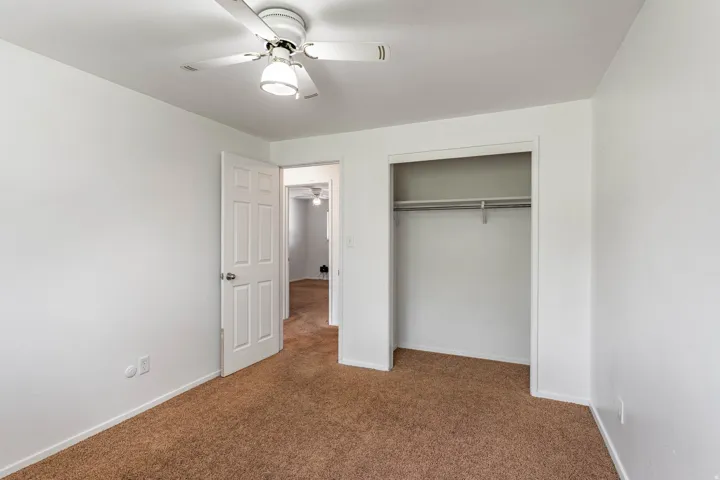 Neutral interior with brown carpet flooring, white walls, and a ceiling fan with integrated lighting