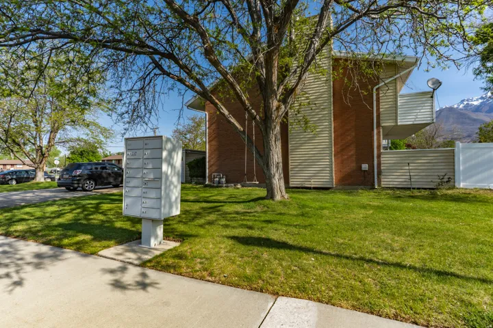 Exterior property featuring a brick facade with horizontal siding, a white privacy fence, and a multi-unit mailbox structure