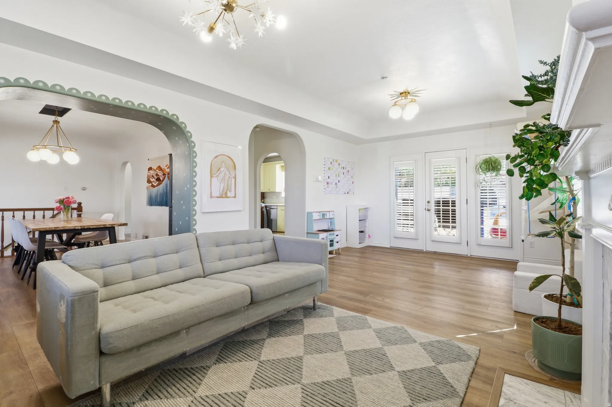 Spacious living area featuring wood-finish flooring, arched doorways, and a decorative fireplace