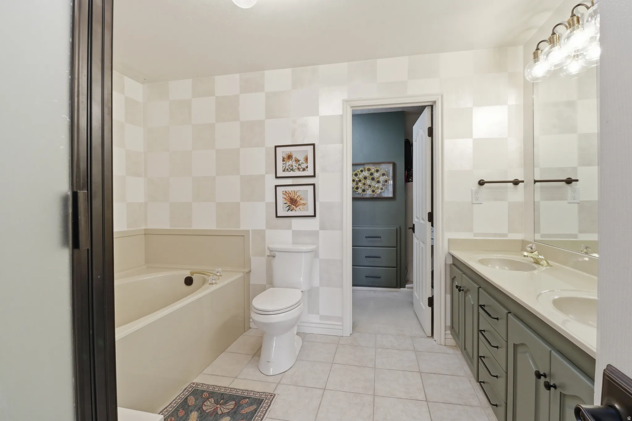 Bathroom featuring a built-in soaking tub, a toilet, and checkered wall covering
