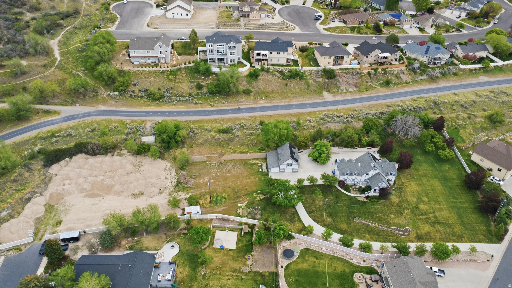 Expansive lot featuring a large graded area, mature trees, and a partially paved driveway