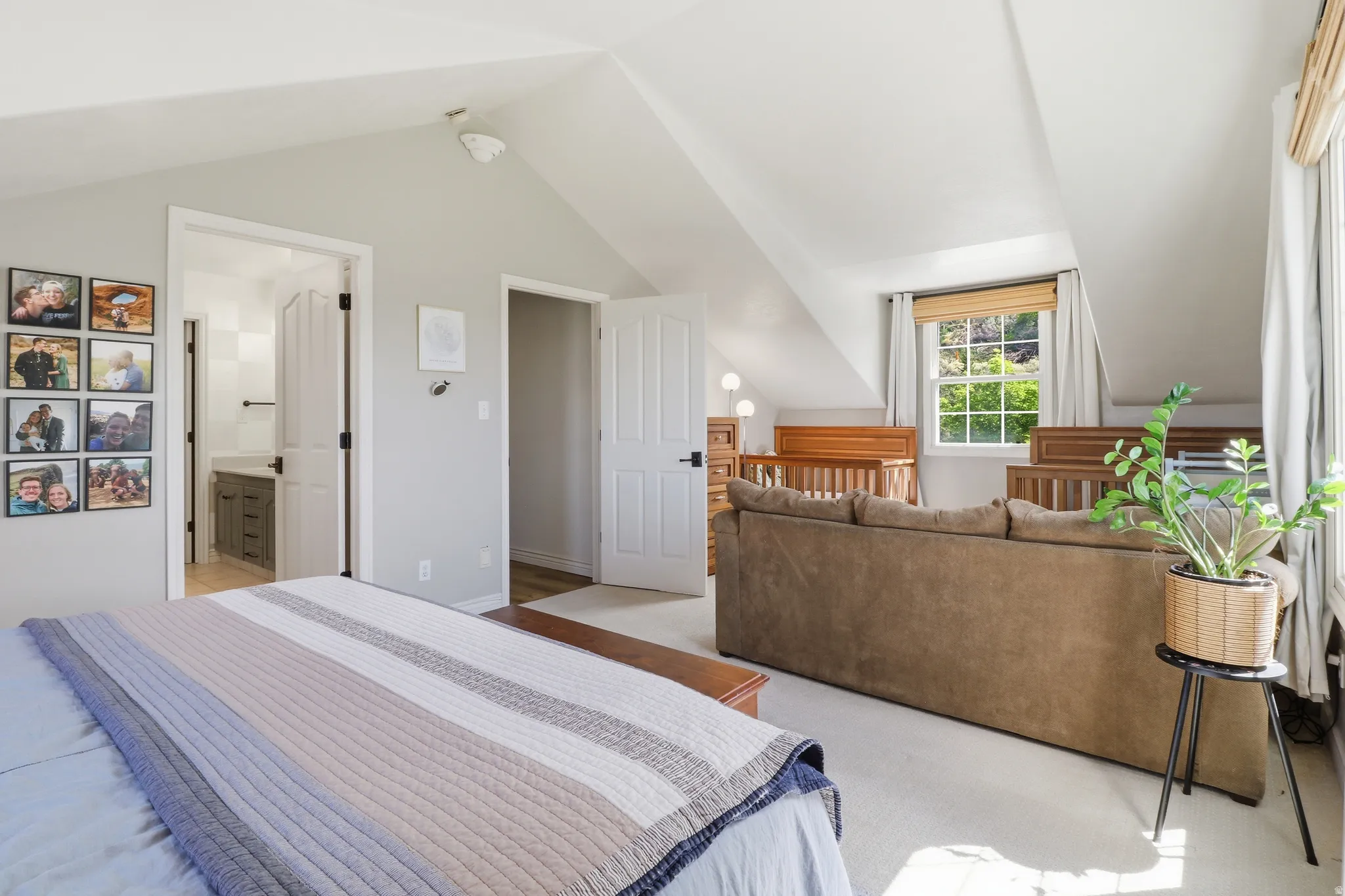 Angled ceiling bedroom featuring light-toned carpet flooring and a window with natural light