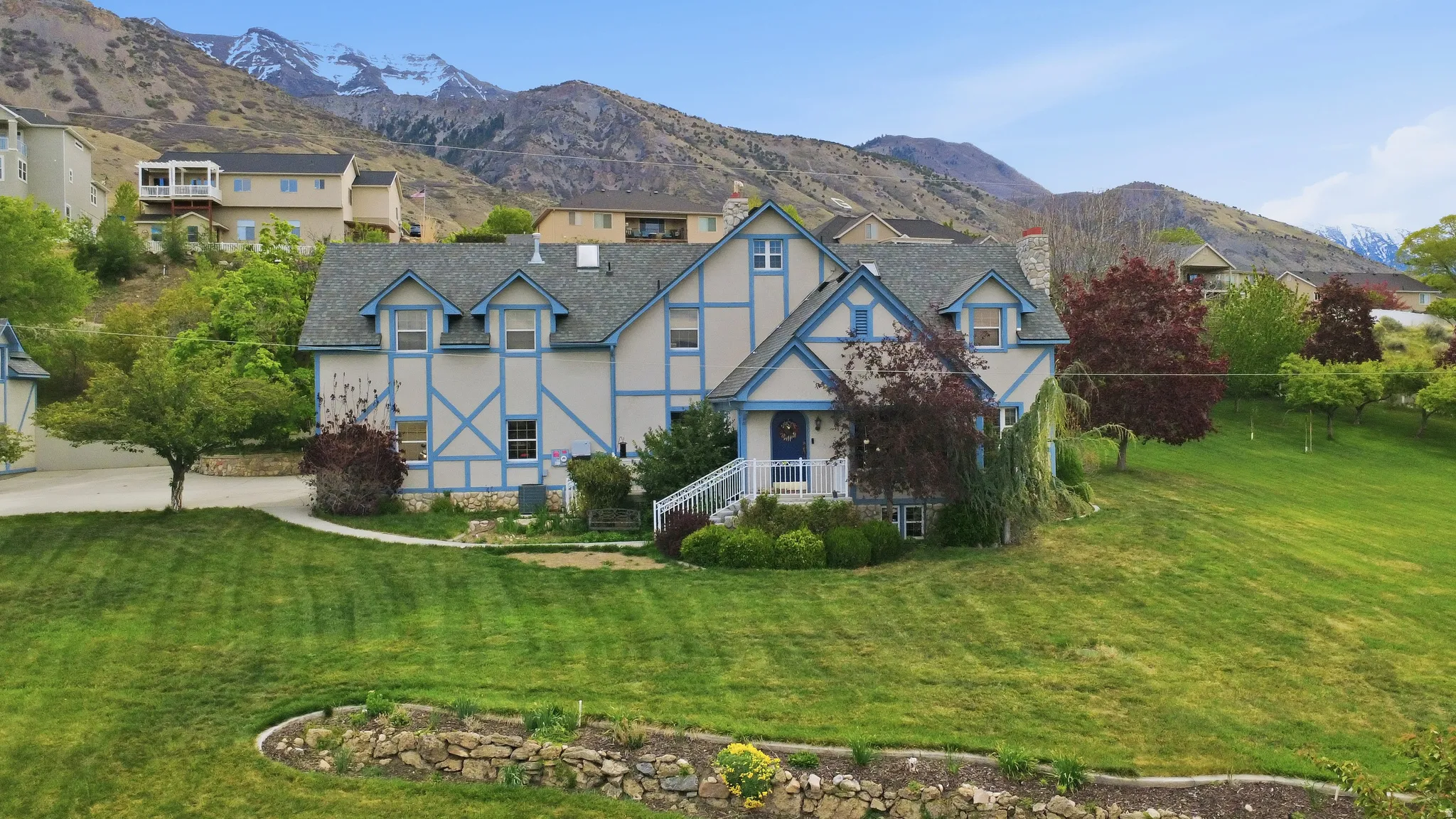 Tudor-style residence with a blue trim facade, gabled rooflines, and a welcoming front porch