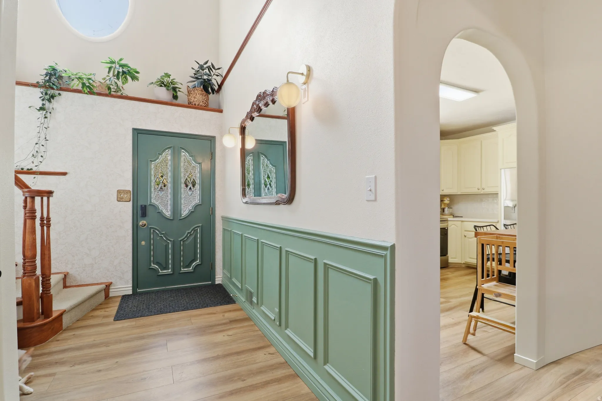Foyer entrance featuring a decorative front door with stained glass inserts, wood-finish flooring, and wainscoting