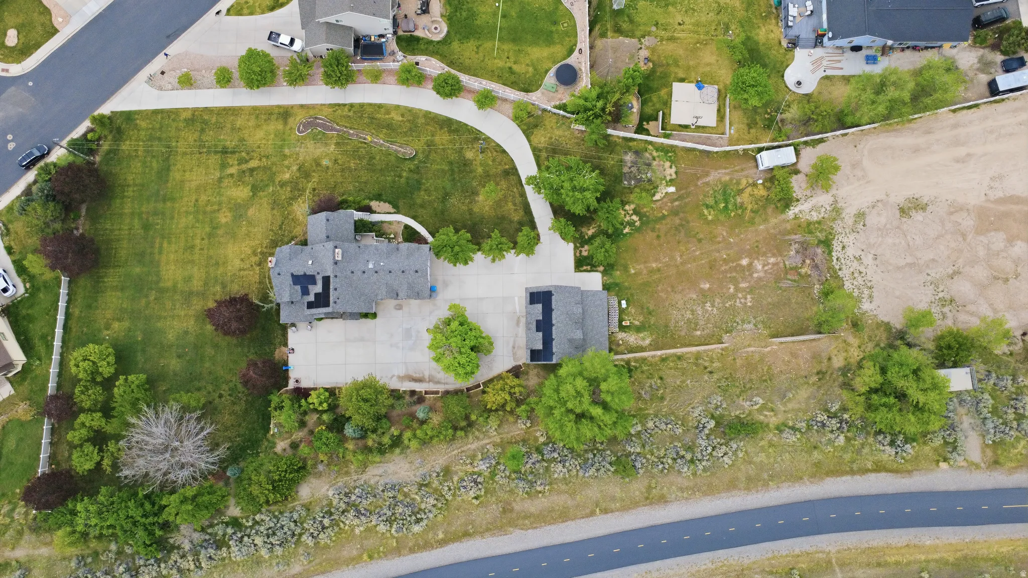 Expansive property featuring a residence with a gray shingle roof, solar panels, and an attached garage