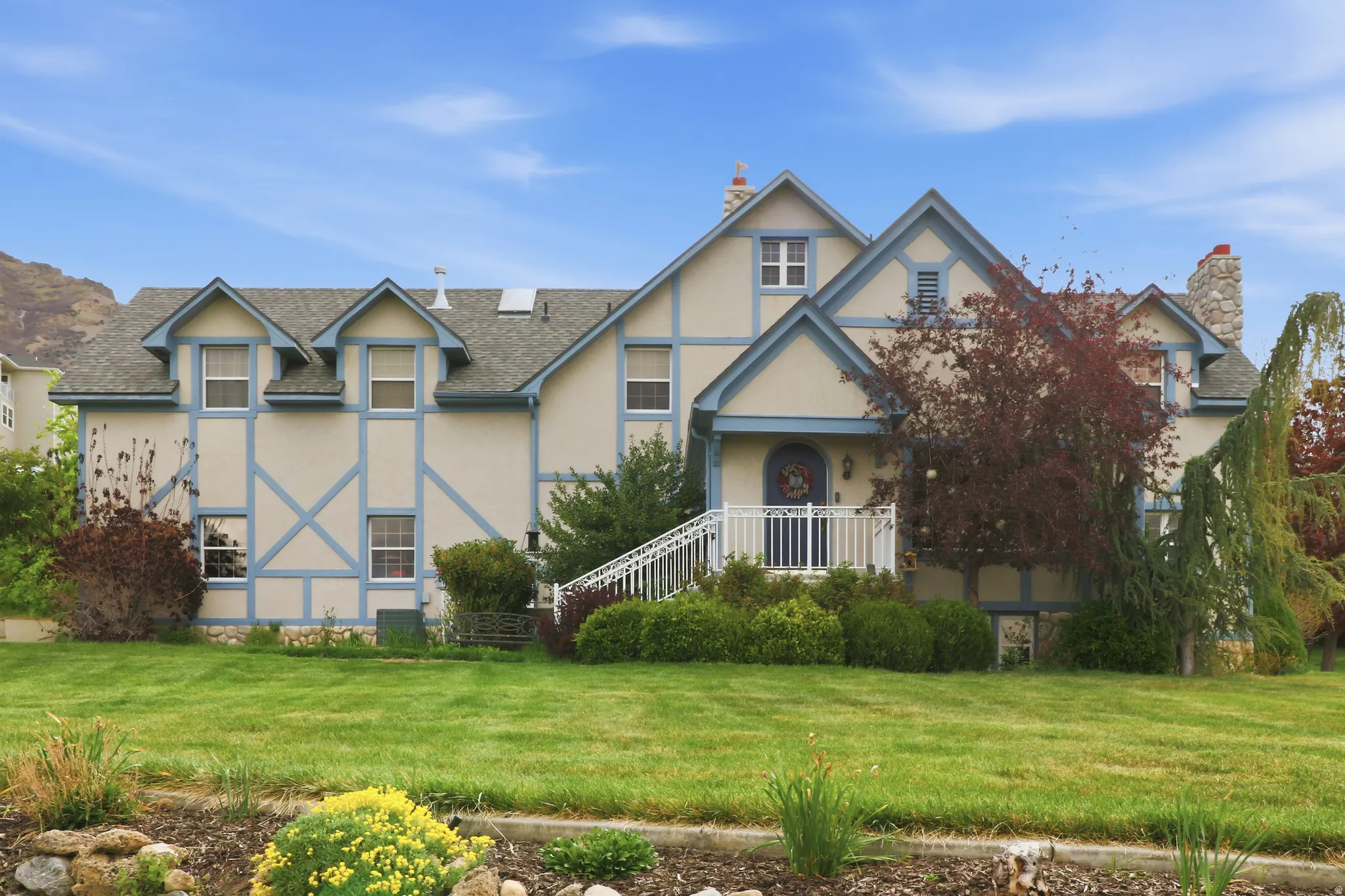 Tudor-style facade with light-colored stucco and blue trim