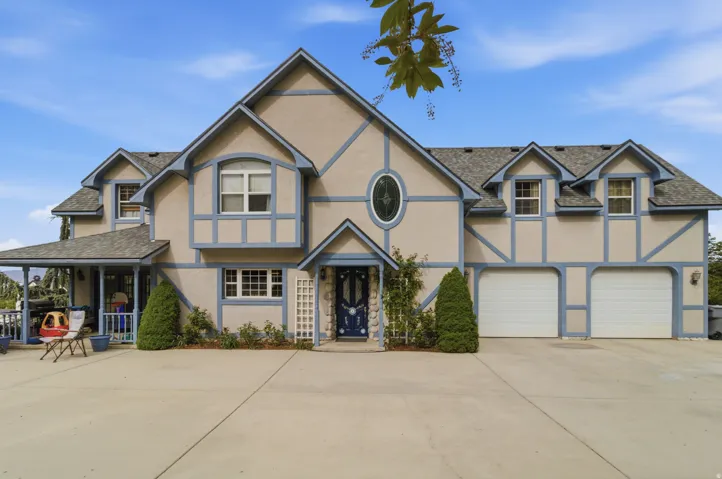 Tudor-style facade featuring prominent gables, light stucco, and contrasting blue trim