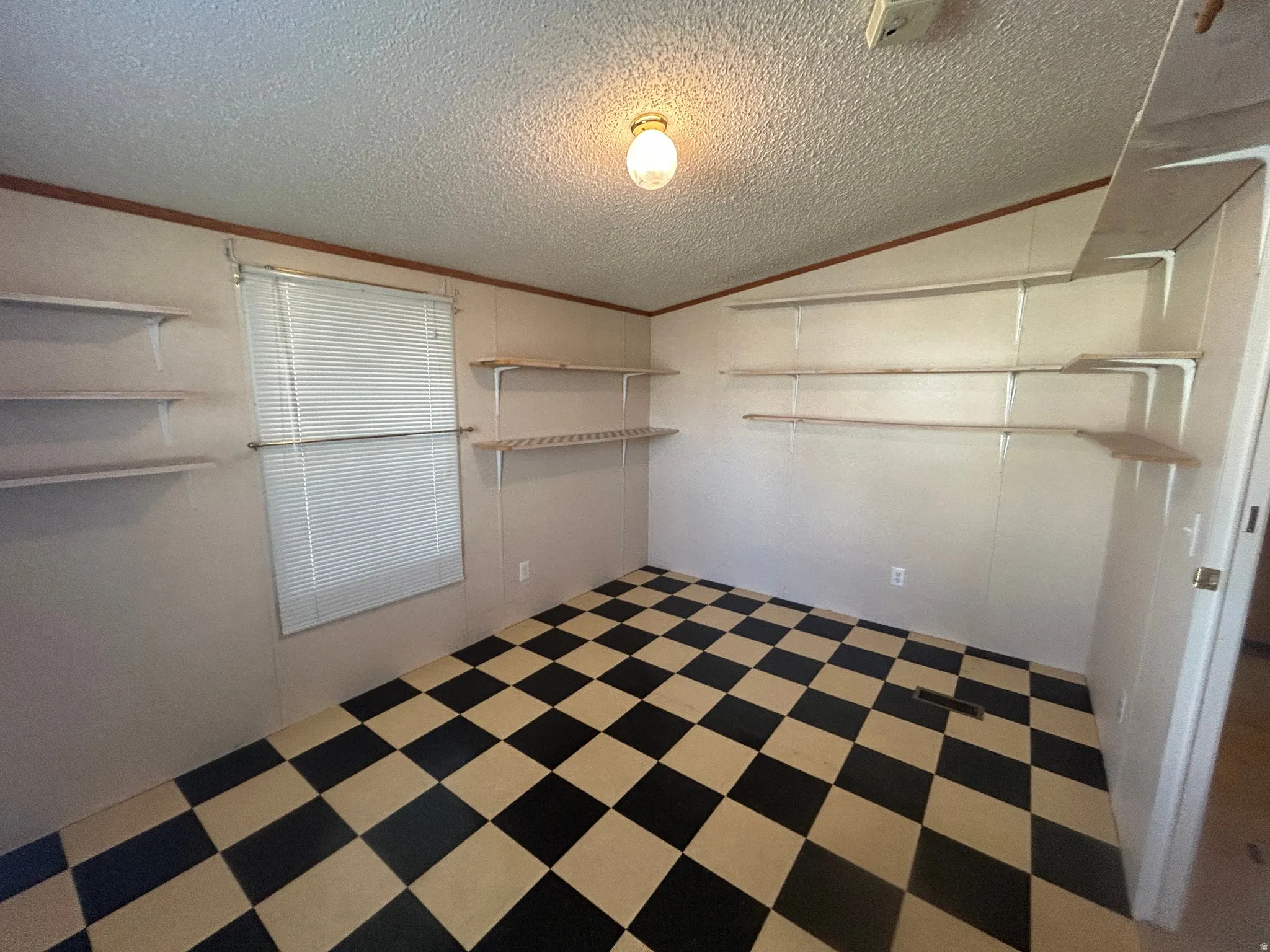 Room featuring checkered flooring, wall-mounted shelving, and a window with horizontal blinds