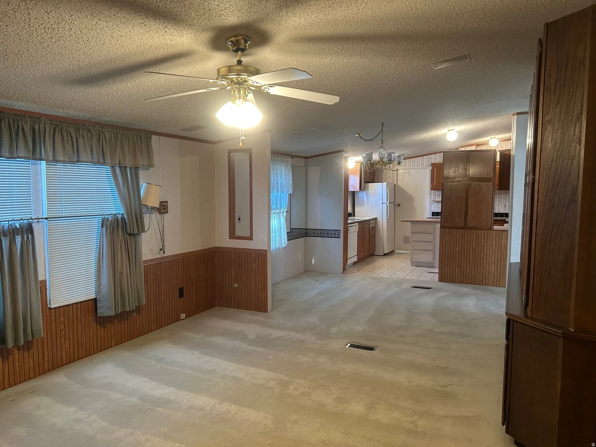 Open-concept living space with carpet flooring and wood-paneled wainscoting