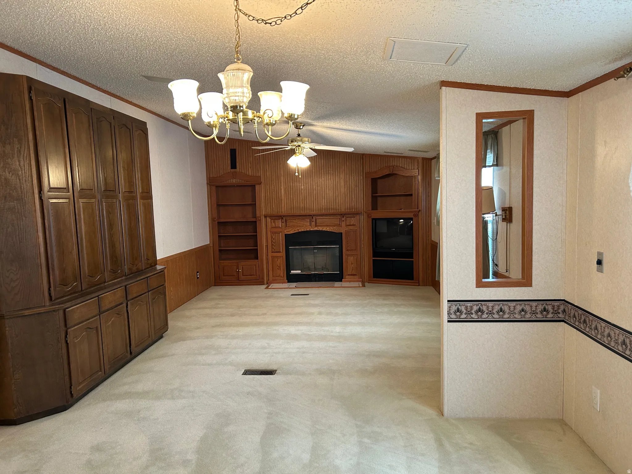 Living area featuring a fireplace with a wood mantle, built-in shelving, and wood-finish wall paneling