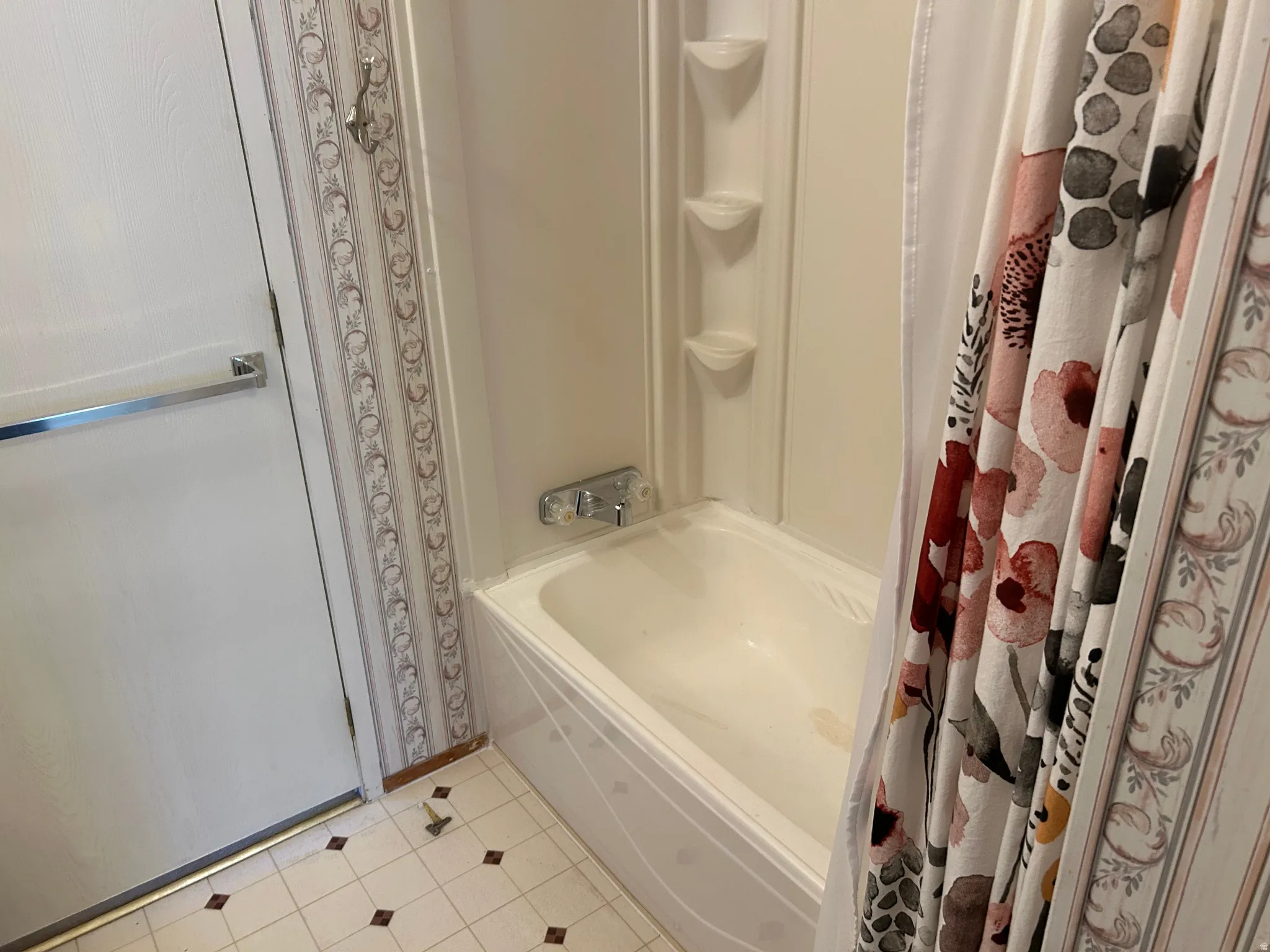 White bathtub with integrated shower, chrome fixtures, and a three-tiered corner caddy