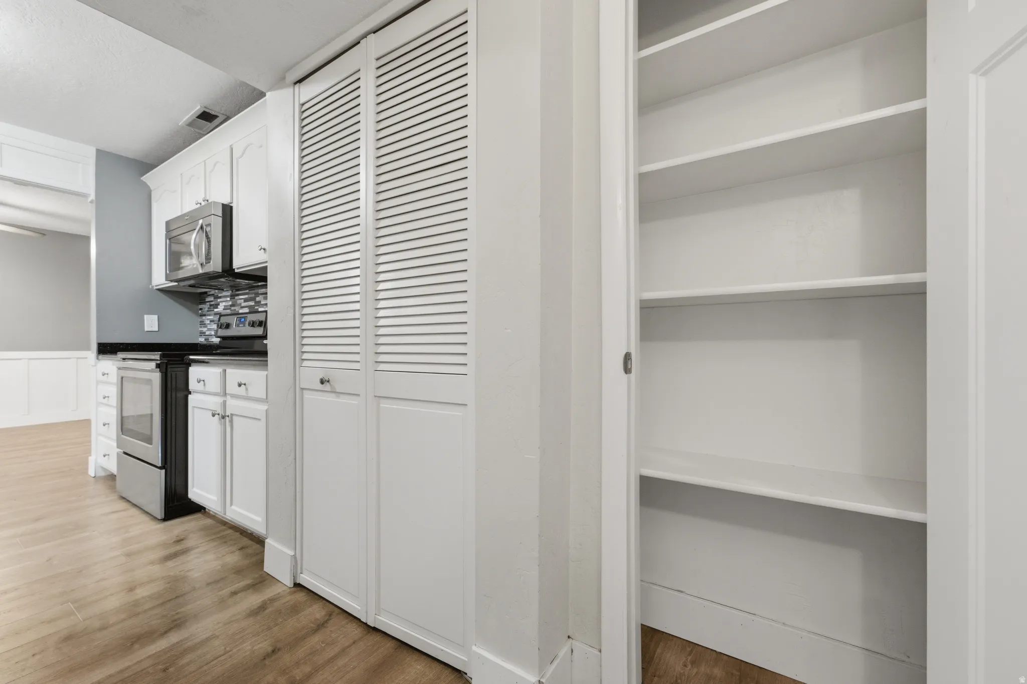 Kitchen area featuring white shaker cabinetry, stainless steel microwave, and built-in electric range