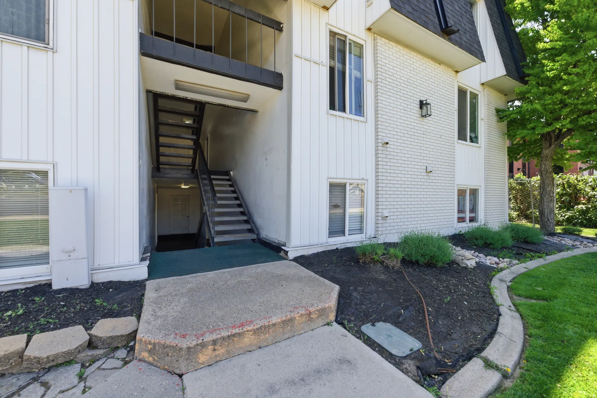 Exterior featuring white vertical siding and painted brick accents