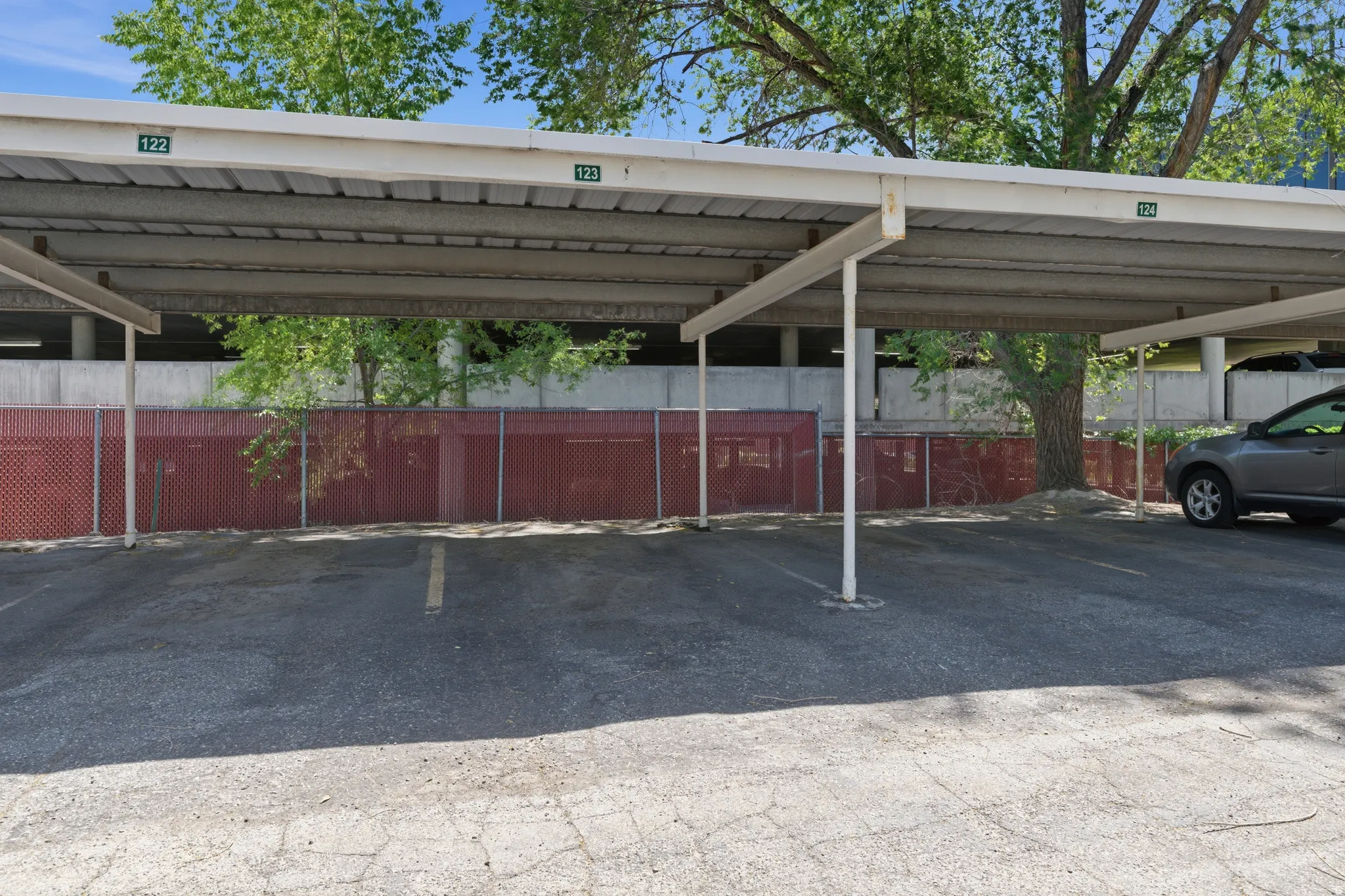 Covered parking structure featuring numbered spaces and a red privacy fence