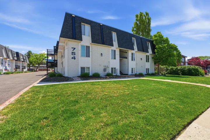 Multi-story building featuring white siding and a dark gambrel roofline