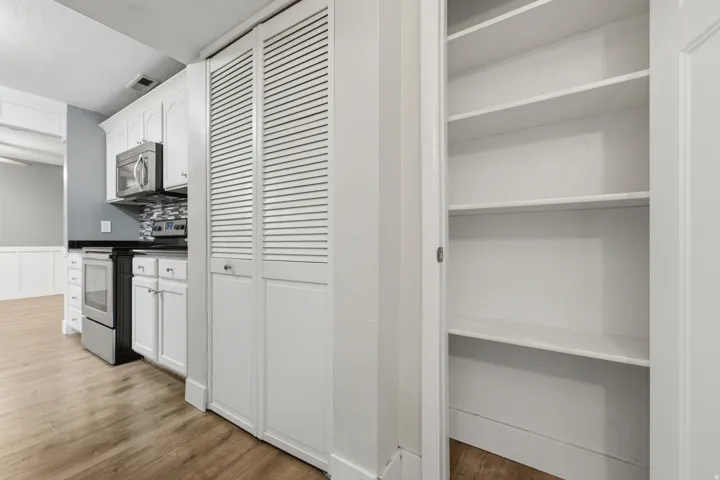 Kitchen area featuring white shaker cabinetry, stainless steel microwave, and built-in electric range
