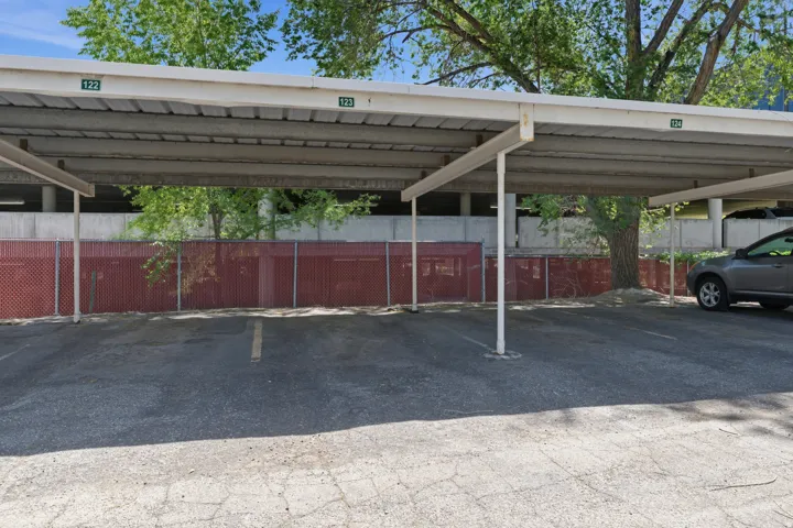 Covered parking structure featuring numbered spaces and a red privacy fence