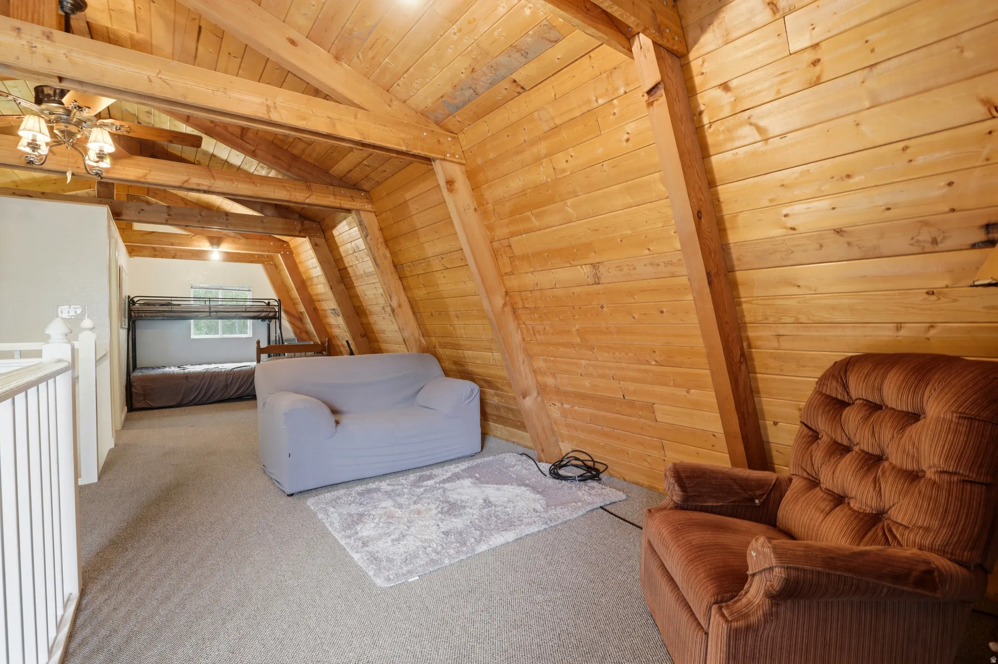 Open loft area featuring exposed wood beams and wood-paneled walls