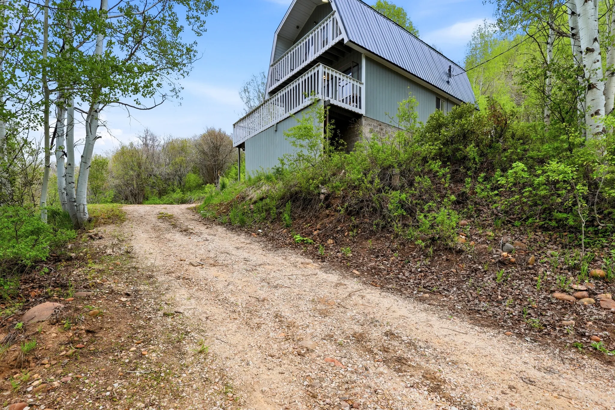 A-frame structure featuring a metal roof, two distinct balconies, and a stone foundation