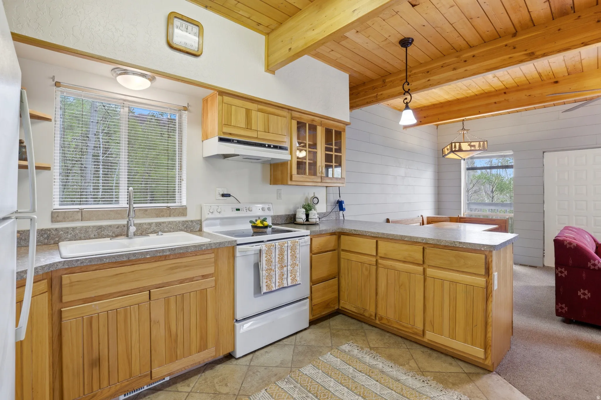 Open-concept kitchen featuring wood cabinetry and white appliances