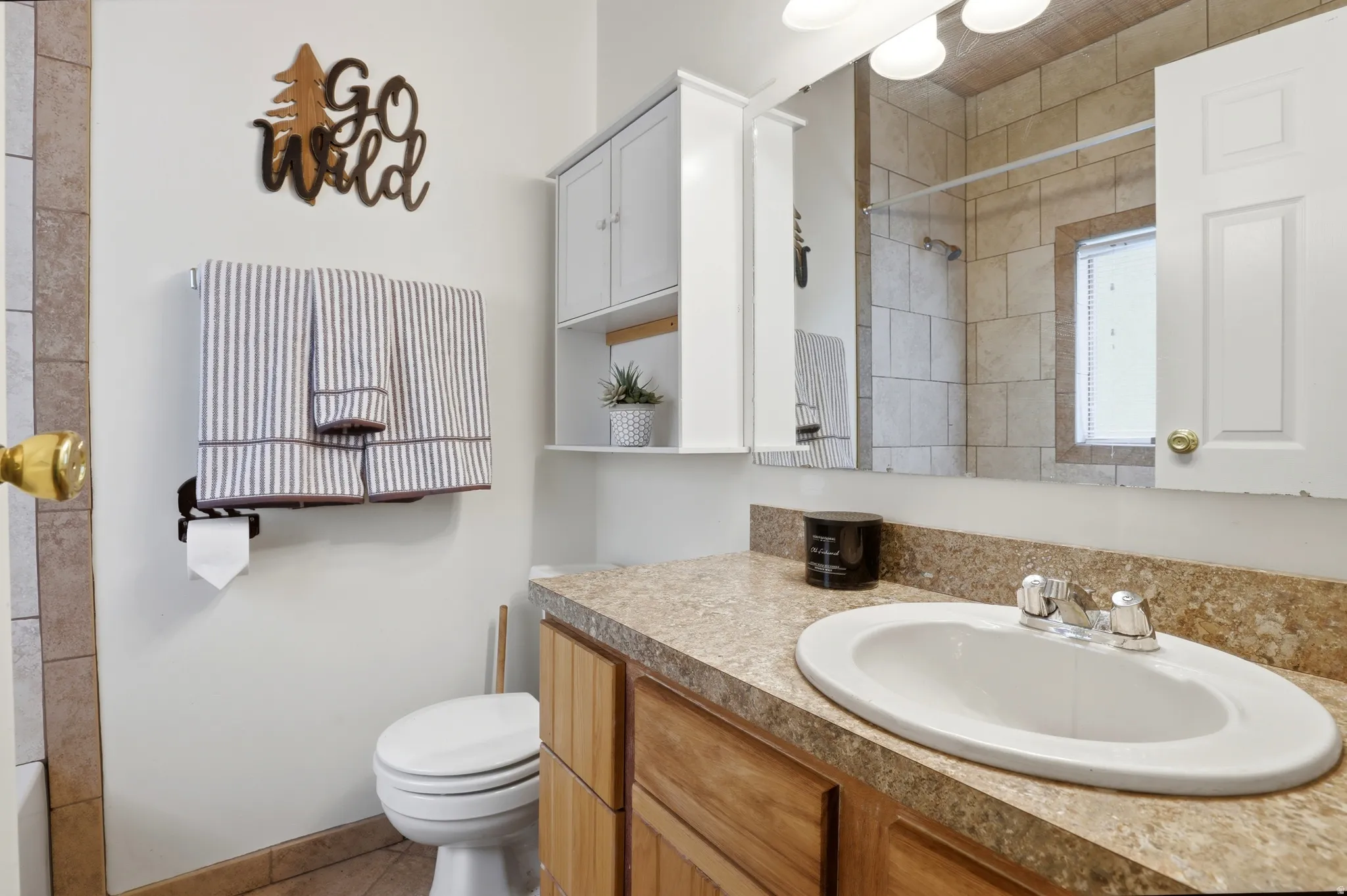 Bathroom featuring a wood-finish vanity with a speckled countertop, an oval-shaped sink, and a chrome faucet