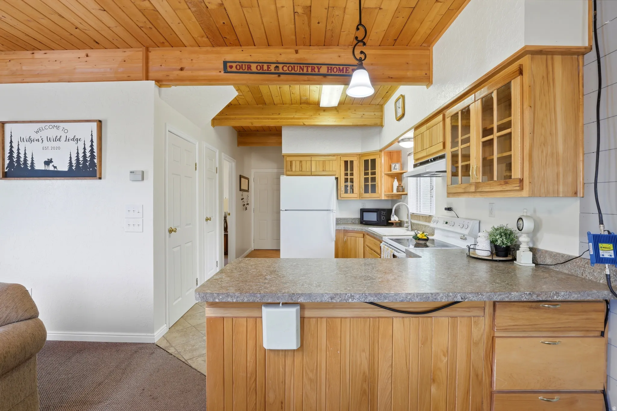 Kitchen featuring a wood-panel breakfast bar with an integrated countertop, wood cabinetry with glass-front uppers, and stainless steel appliances