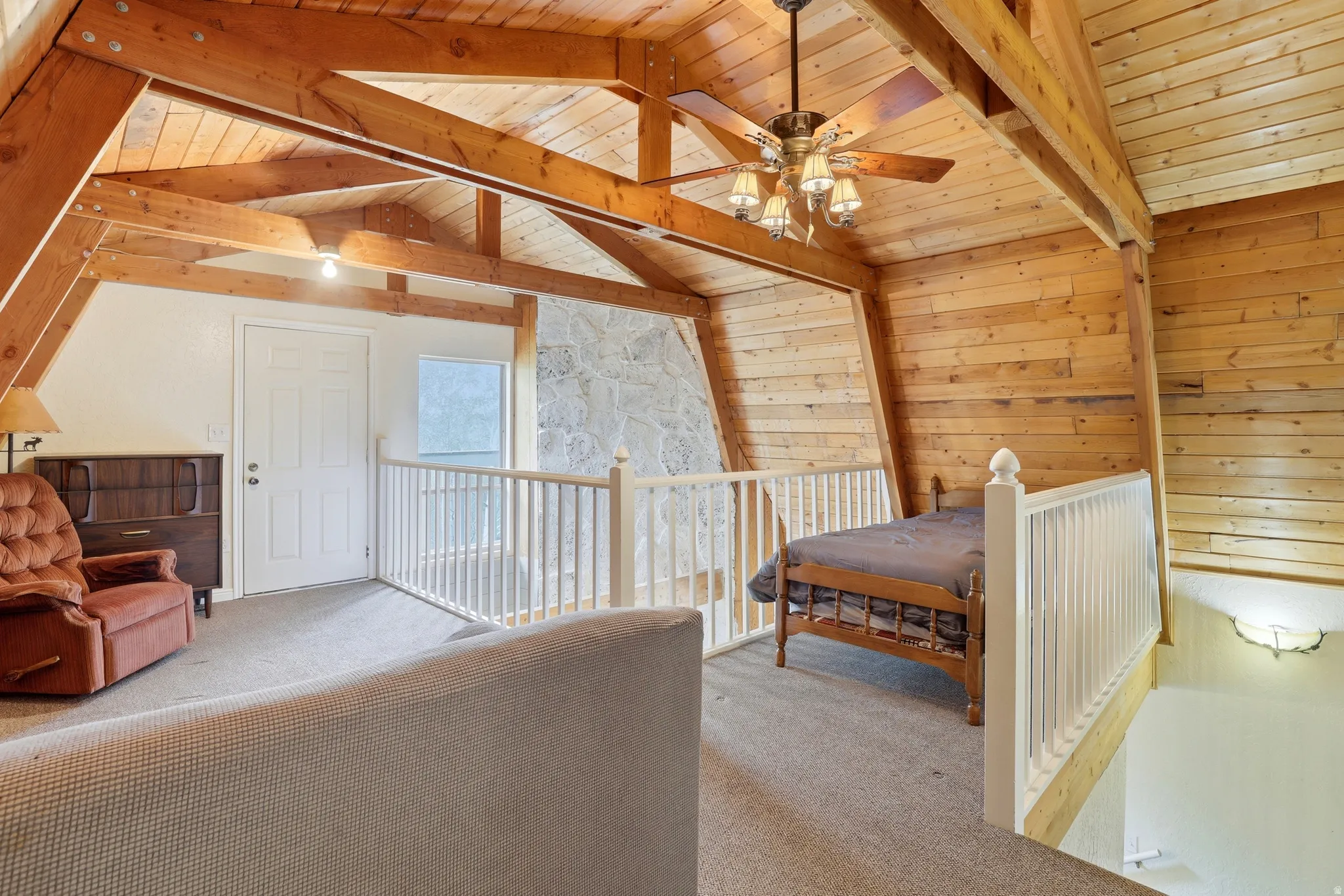 Exposed wood-beam vaulted ceilings featuring a ceiling fan with light fixture