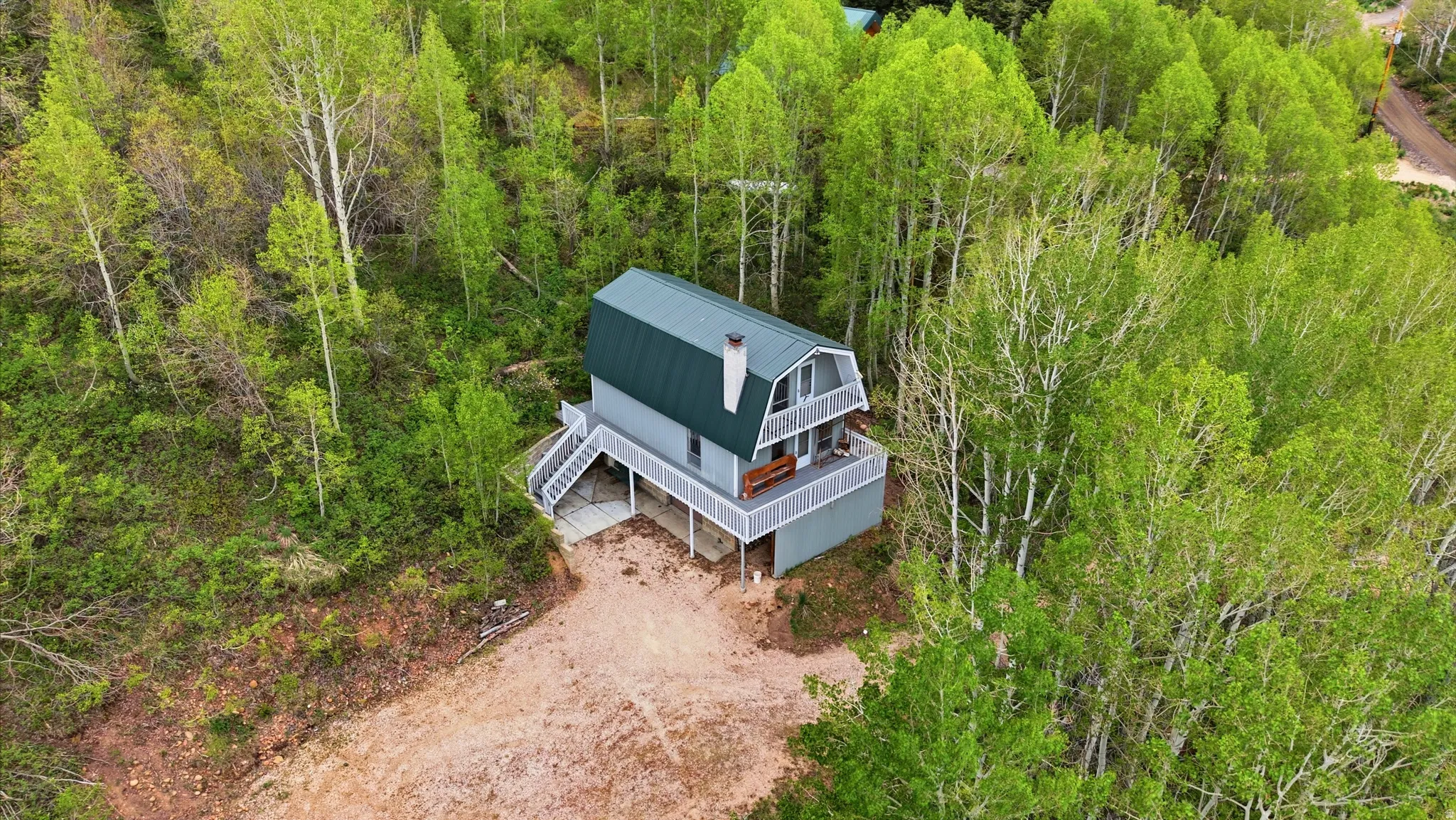 Gambrel roofline property surrounded by mature trees