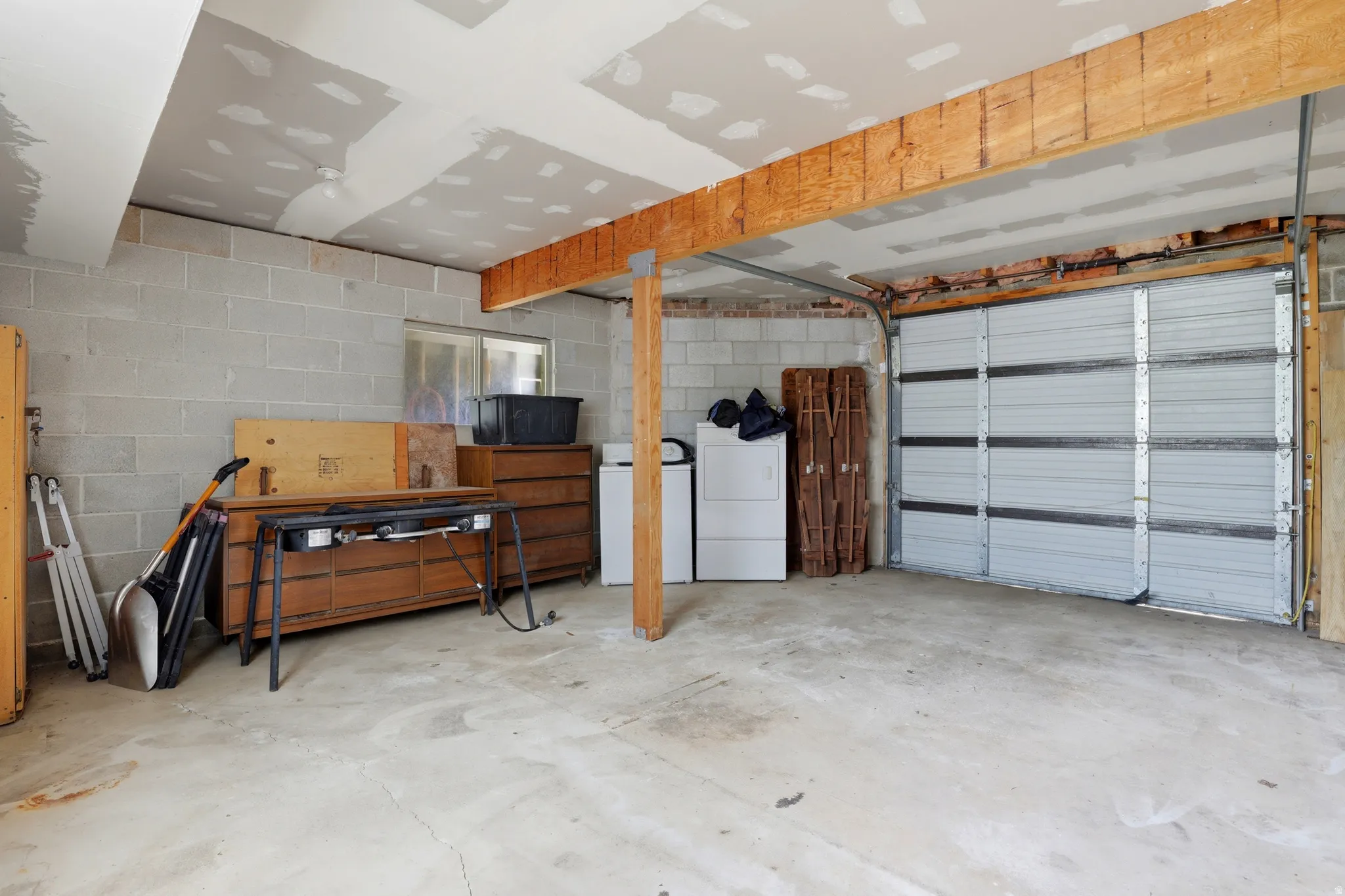 Spacious garage with concrete block walls, exposed wood ceiling joists, and a sectional overhead door