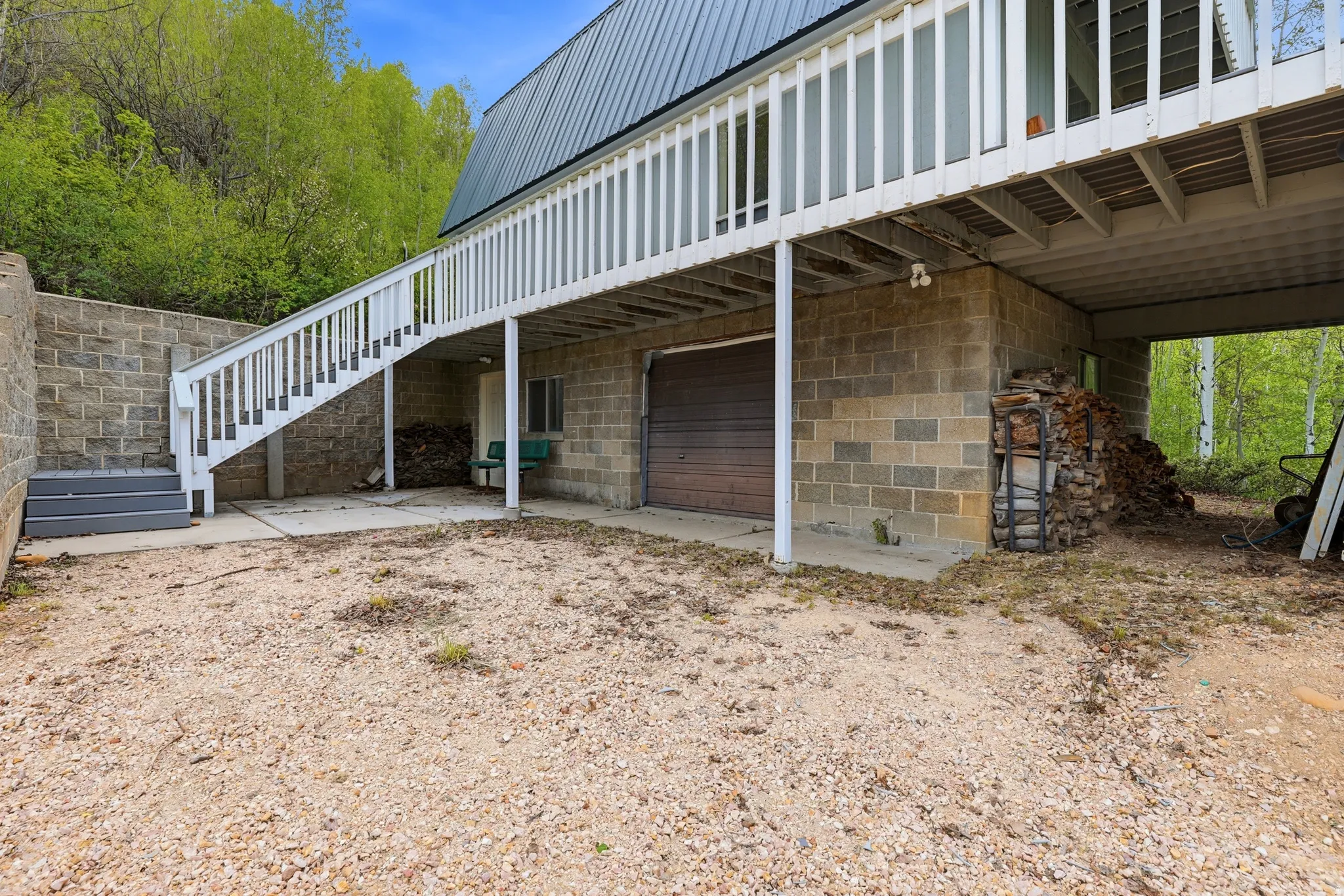 Lower-level exterior featuring a block foundation, attached garage with a brown door, and a concrete patio area